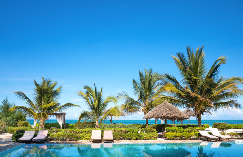 a resort pool with lounge chairs and palm trees